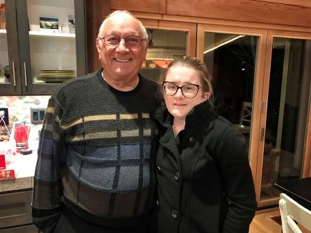 James Thoms standing in a kitchen with his grand-daughter Camille in his arms